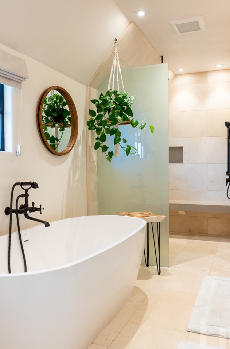 Spa bath with freestanding tub, hanging greenery, and soft natural light