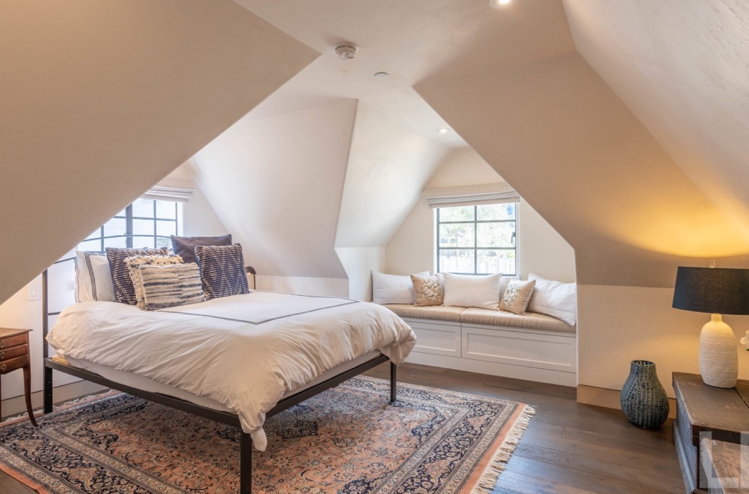 Vaulted loft bedroom with window seat and warm evening light