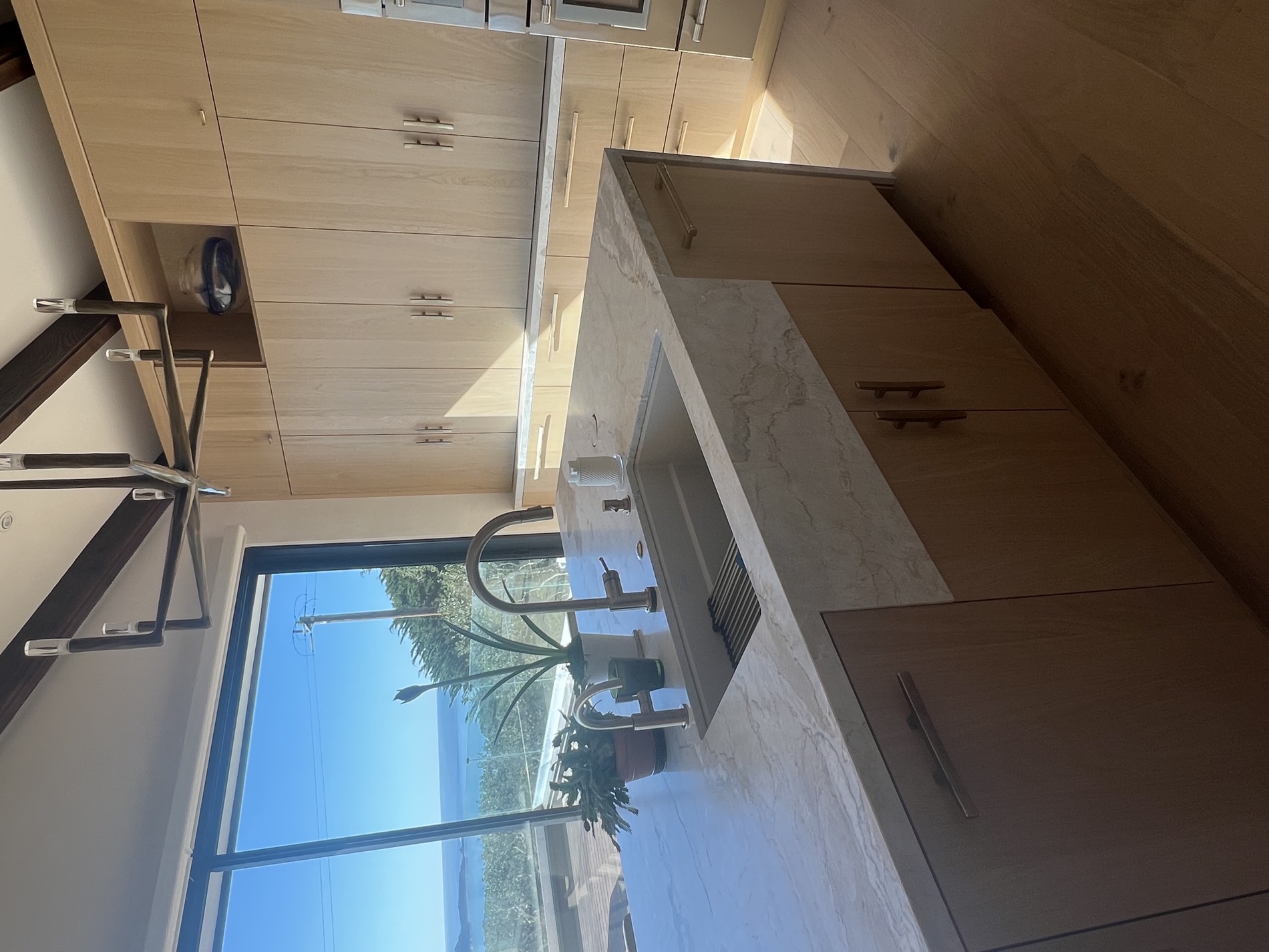 Ocean-view kitchen with white oak cabinetry and marble above the bay