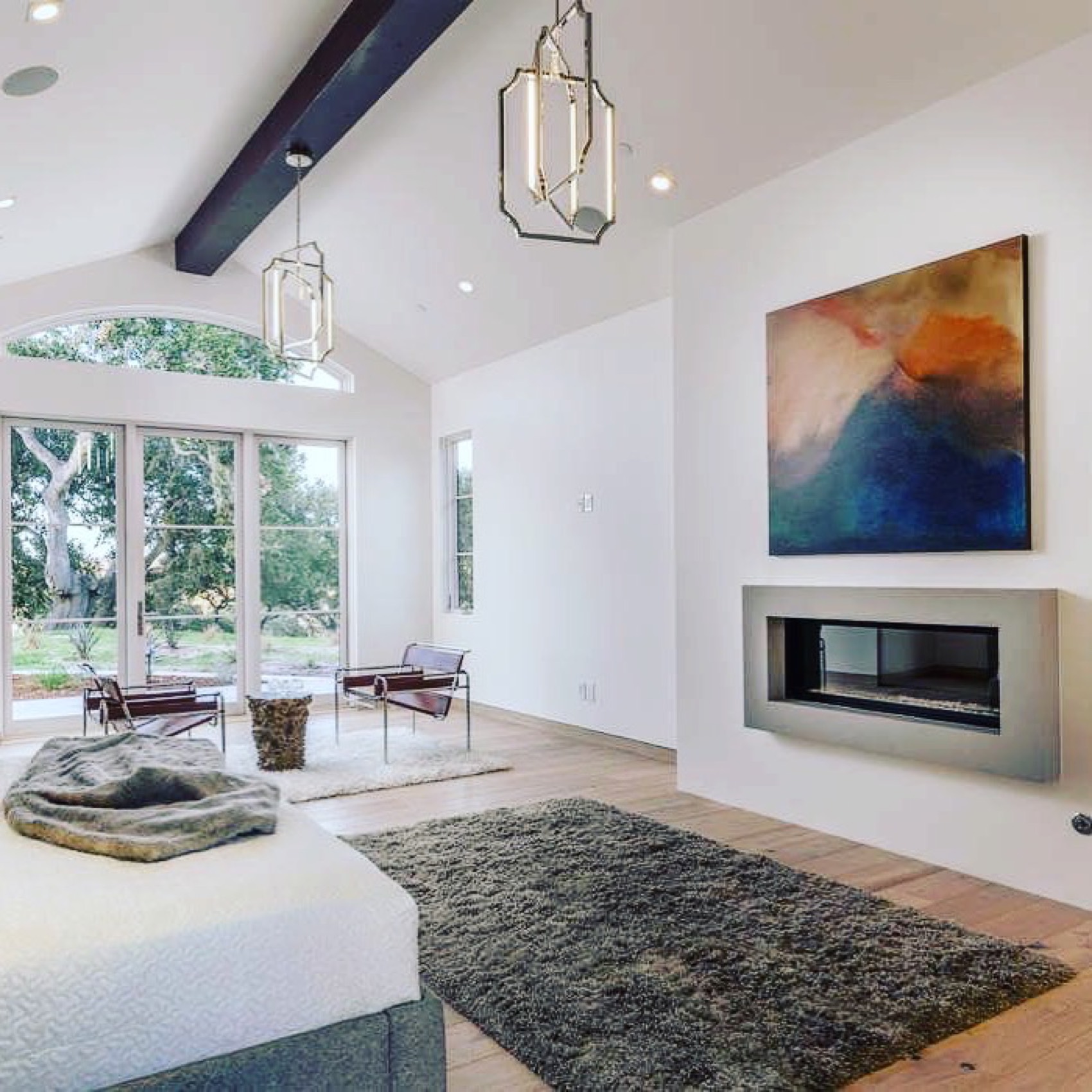 Bright living room with vaulted beams, abstract canvas, and modern fireplace